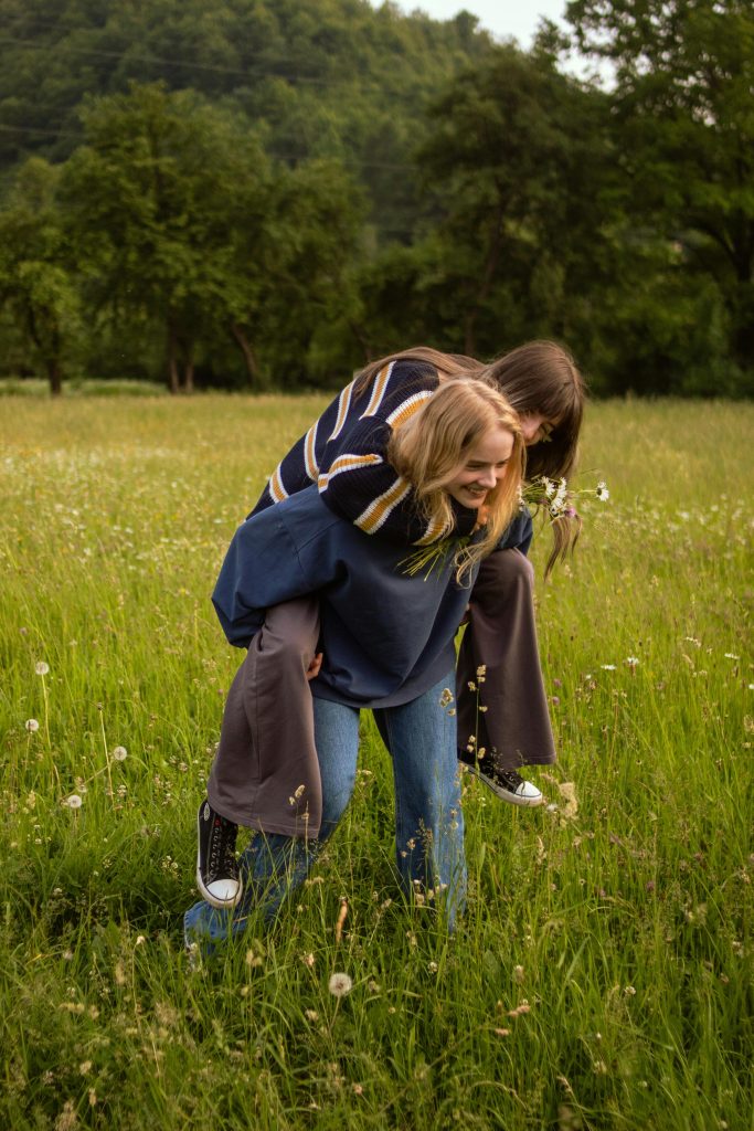 pexels photo 32523802 32523802 Two friends enjoying a piggyback ride in a vibrant green meadow filled with wildflowers.